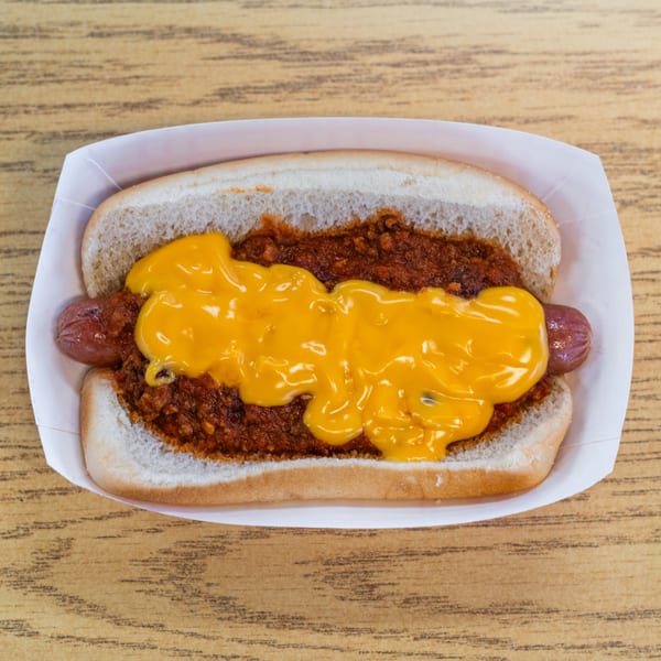 A chili cheese dog from 5 Points Restaurant, served in a paper tray on a wooden table.